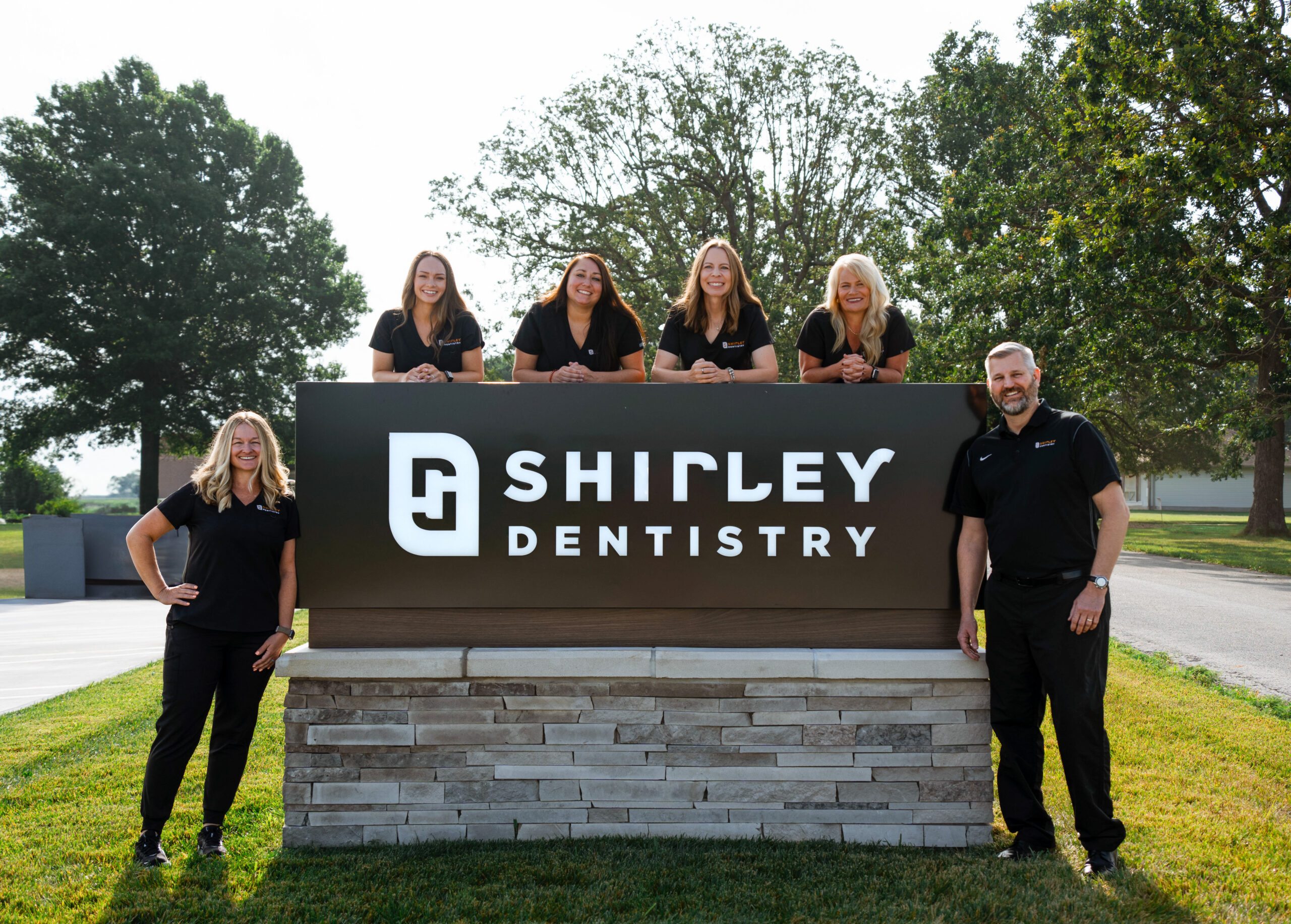Dental staff posing around exterior Shirley Dentistry sign